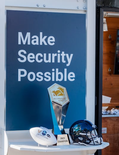 The ReliaQuest Bowl trophy on display beneath a Make Security Possible sign