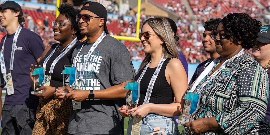 Make It Possible community honorees holding their awards on the field