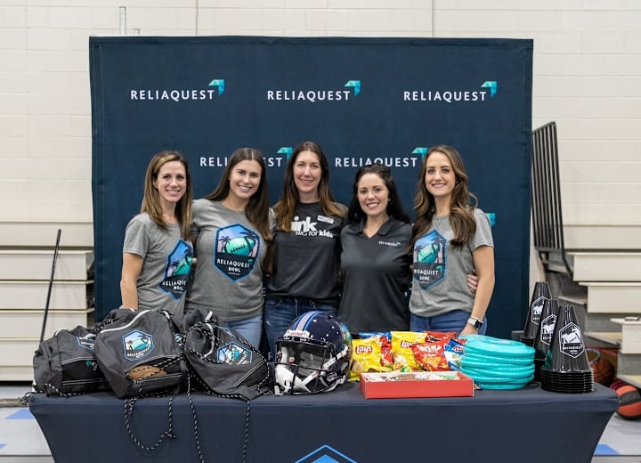 ReliaQuest teammates at a ReliaQuest Bowl swag table