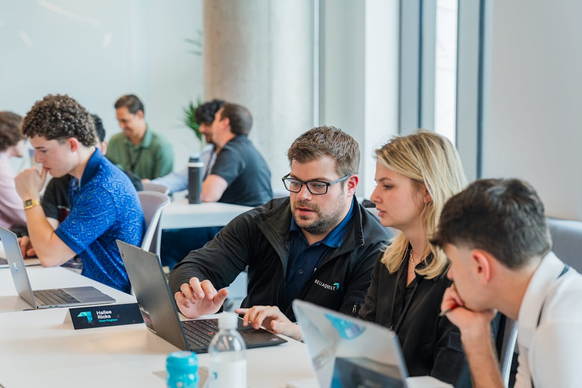 A ReliaQuest engineer working through a problem with Cybersecurity Labs students